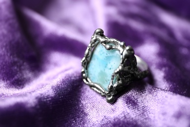 Beautiful silver ring with larimar gemstone on violet fabric, closeup