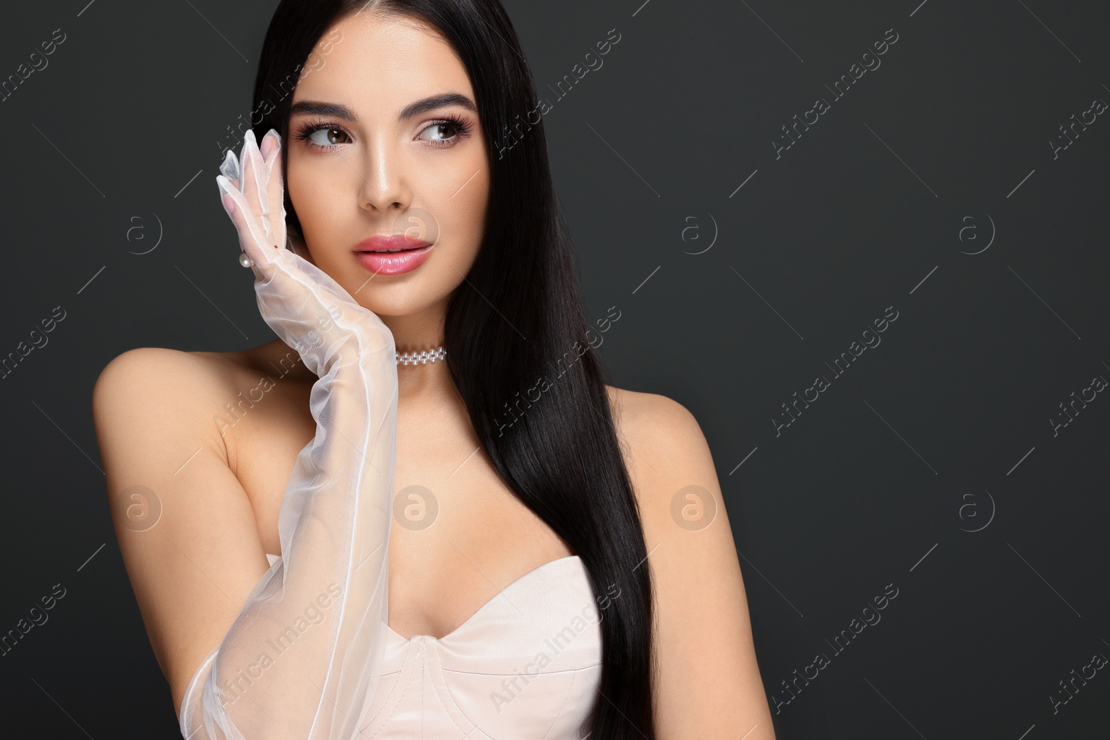 Photo of Portrait of beautiful young woman in evening gloves on black background. Space for text