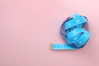 Photo of Light blue measuring tape on pink background, top view. Space for text