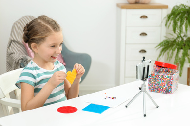 Photo of Cute little blogger with handcrafting recording video at home