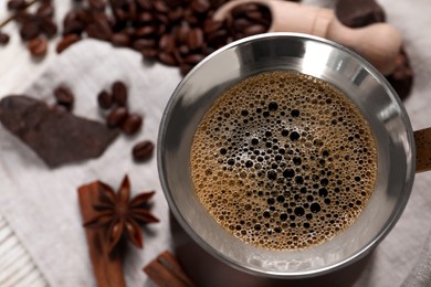 Photo of Turkish coffee pot with hot drink, beans and spices on table, above view. Space for text