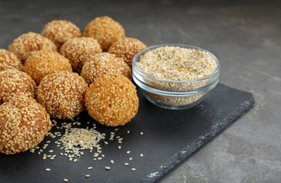 Photo of Delicious sesame balls and seeds on grey table