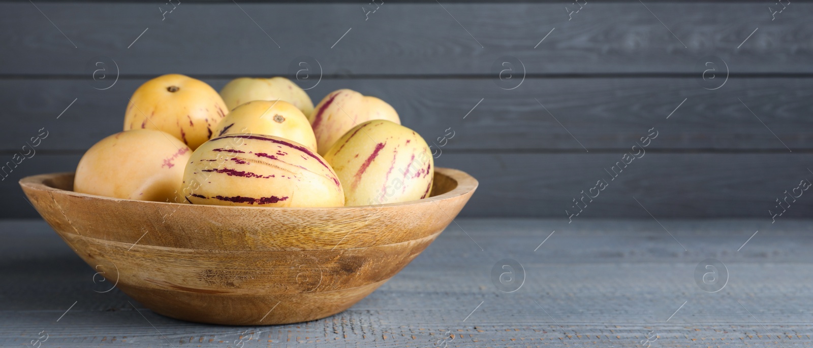 Image of Fresh ripe pepino melons on grey wooden table, space for text. Banner design