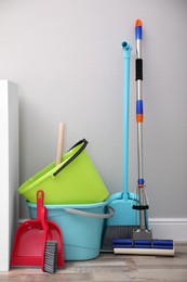 Photo of Set of cleaning tools and accessories near light grey wall indoors