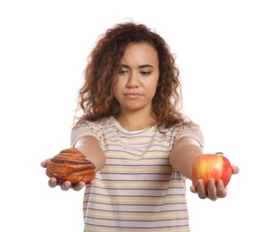 Photo of Young African-American woman with pastry and apple on white background. Diabetes diet