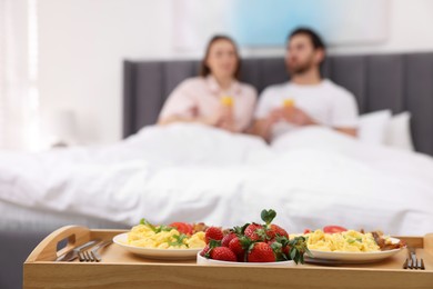 Photo of Tasty breakfast on tray, selective focus. Lovely couple spending time together in bedroom