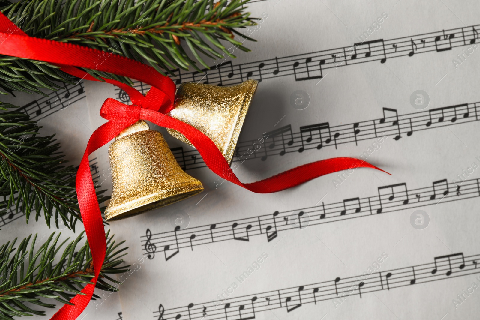 Photo of Bells and fir tree branches on music sheet, flat lay. Christmas decor