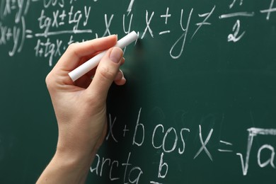 Photo of Teacher writing down math equation on green board, closeup