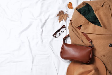 Photo of Flat lay composition with stylish hat and autumn clothes on white fabric, space for text