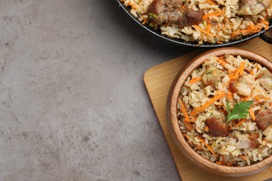Photo of Delicious pilaf with meat and carrot on grey textured table, flat lay. Space for text