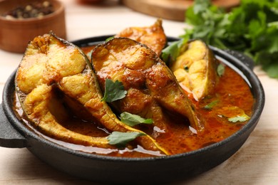 Photo of Tasty fish curry on white wooden table, closeup. Indian cuisine