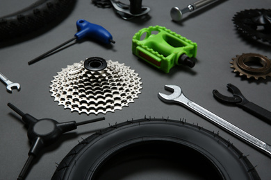 Photo of Set of different bicycle tools and parts on grey background, closeup