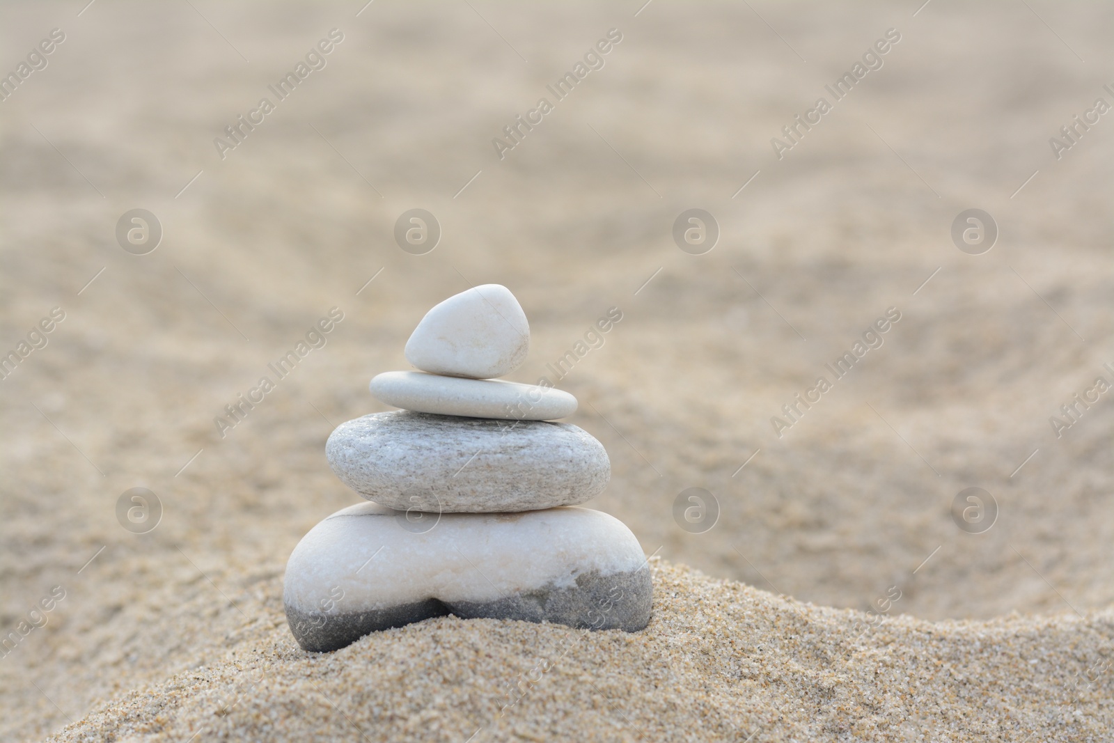 Photo of Stack of stones on sandy beach, space for text