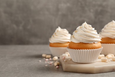 Photo of Delicious cupcakes decorated with cream on light grey table. Space for text