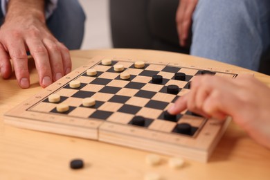 Photo of People playing checkers at wooden table, closeup