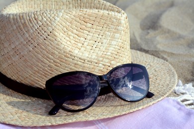 Photo of Hat with beautiful sunglasses on blanket, closeup