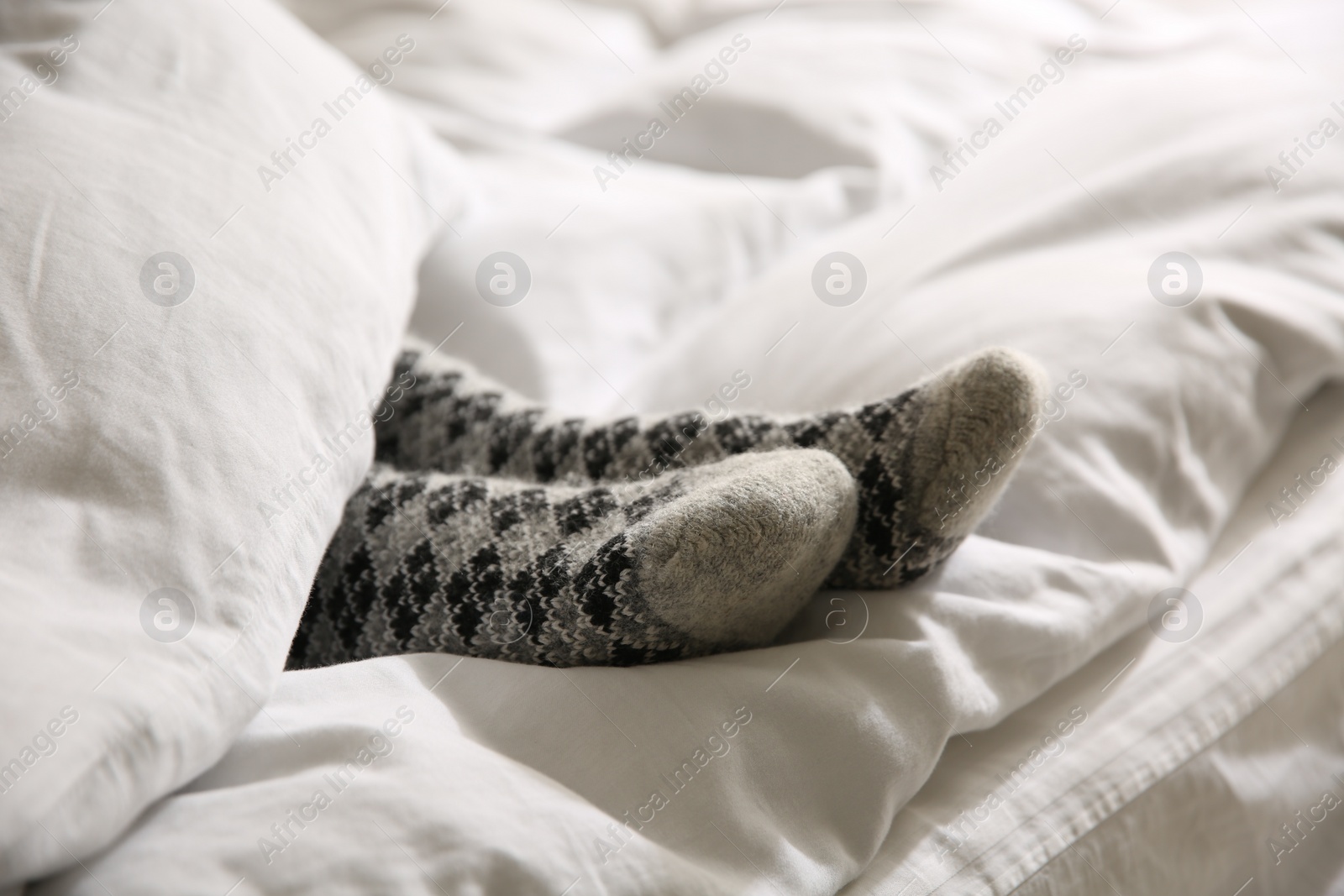 Woman wearing knitted socks under blanket in bed, closeup Photo of Woman wearing knitted socks under blanket in bed, closeup