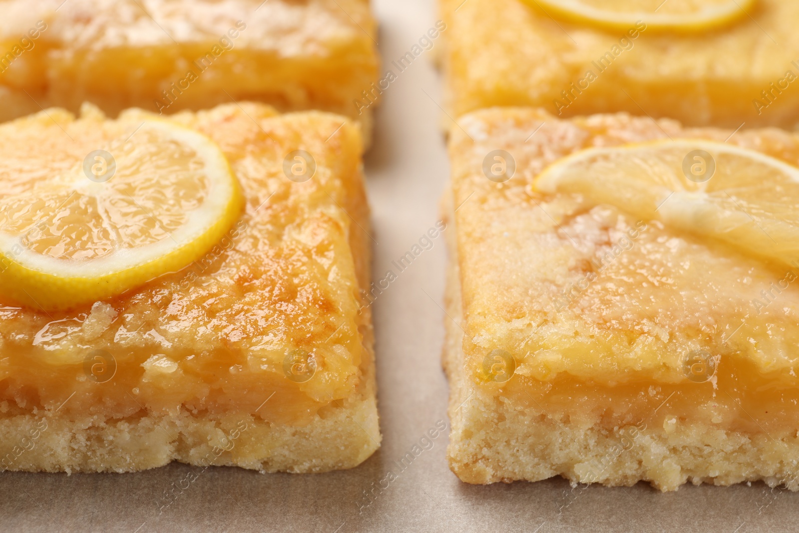Tasty lemon bars on parchment paper, closeup Photo of Tasty lemon bars on parchment paper, closeup