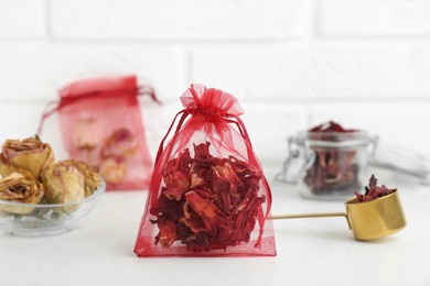 Photo of Scented sachet with dried hibiscus flowers on white table