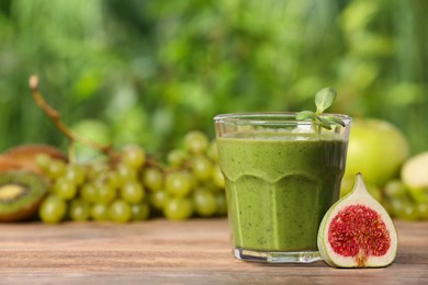 Photo of Glass of fresh green smoothie and ingredients on wooden table outdoors, space for text