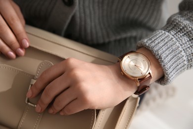 Photo of Woman with luxury wristwatch and handbag on blurred background, closeup