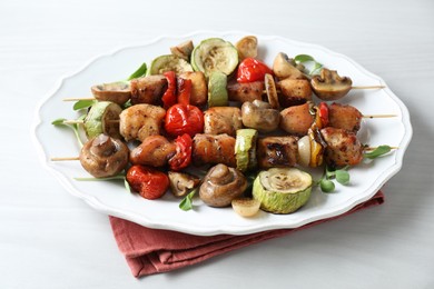 Photo of Delicious shish kebabs with vegetables and microgreens on white table, closeup