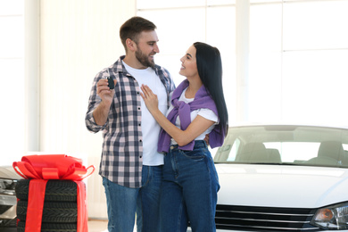 Photo of Happy couple with car key in modern auto dealership