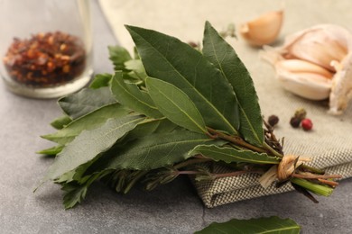 Photo of Aromatic bay leaves and different herbs on light gray table, closeup