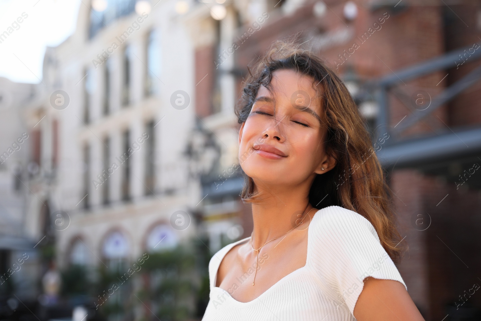 Photo of Portrait of happy young woman on city street. Space for text