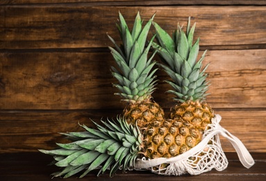 Photo of Bag with fresh juicy pineapples on wooden table