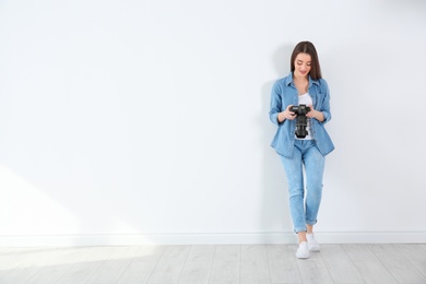 Photo of Female photographer with camera near light wall indoors