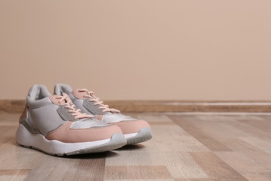 Photo of Pair of sport shoes on floor near color wall, space for text