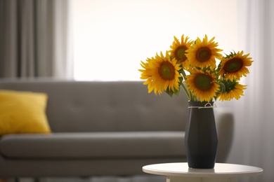 Photo of Vase with beautiful yellow sunflowers on table in room, space for text