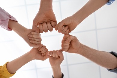 Photo of People holding fists together indoors, bottom view