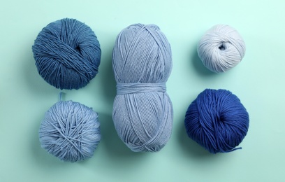 Photo of Soft woolen yarns on light blue background, flat lay