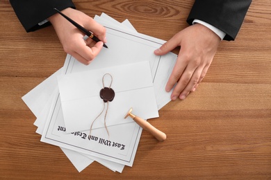 Photo of Male notary working at wooden table, top view