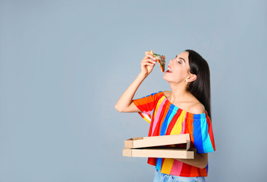 Beautiful woman with pizza on grey background, space for text