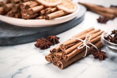Photo of Aromatic cinnamon sticks and anise on white marble table