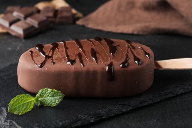 Photo of Delicious glazed ice cream and mint on black table, closeup