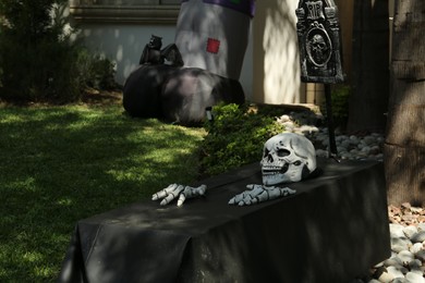 Photo of Skeleton crawling out of black coffin outdoors. Halloween decor