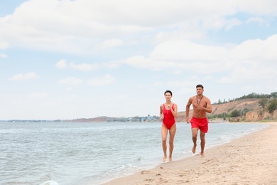 Professional lifeguards running at sandy beach on sunny day