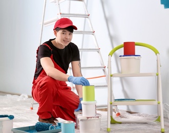 Photo of Male decorator with paint buckets indoors