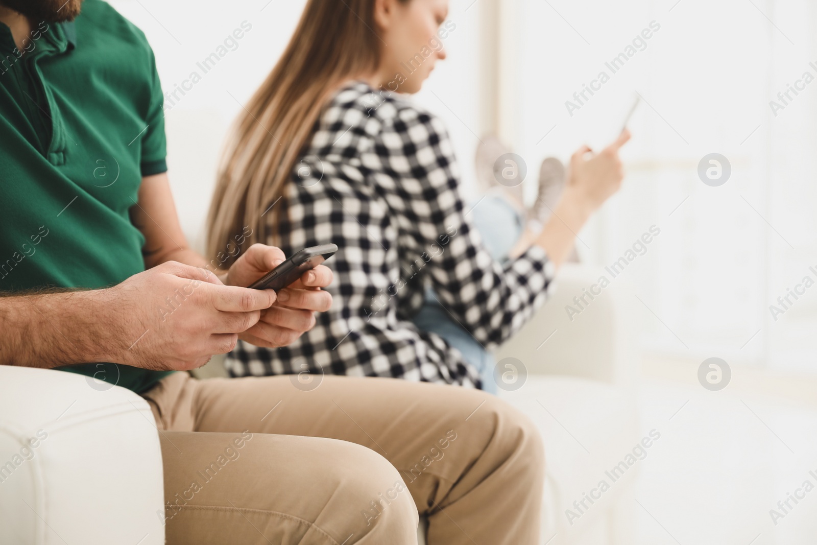 Photo of Couple addicted to smartphones at home, closeup. Relationship problems