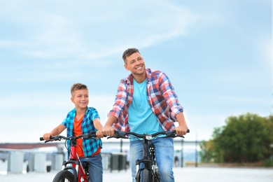 Photo of Dad and son riding bicycles together outdoors