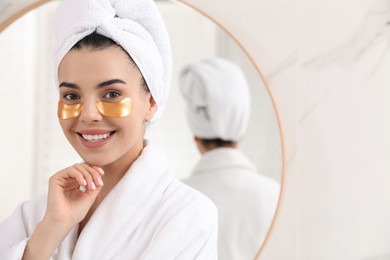 Beautiful young woman with under eye patches at home, space for text
