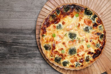 Photo of Delicious homemade quiche with salmon and broccoli on wooden table, top view. Space for text