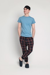 Photo of Happy man in pyjama and sleep mask on light grey background