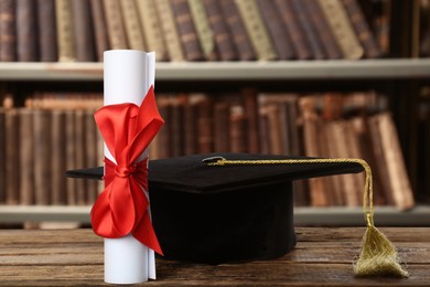 Image of Graduation hat and diploma on wooden table in library