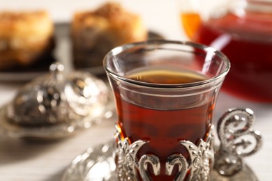 Photo of Glass of traditional Turkish tea in vintage holder on table, closeup. Space for text