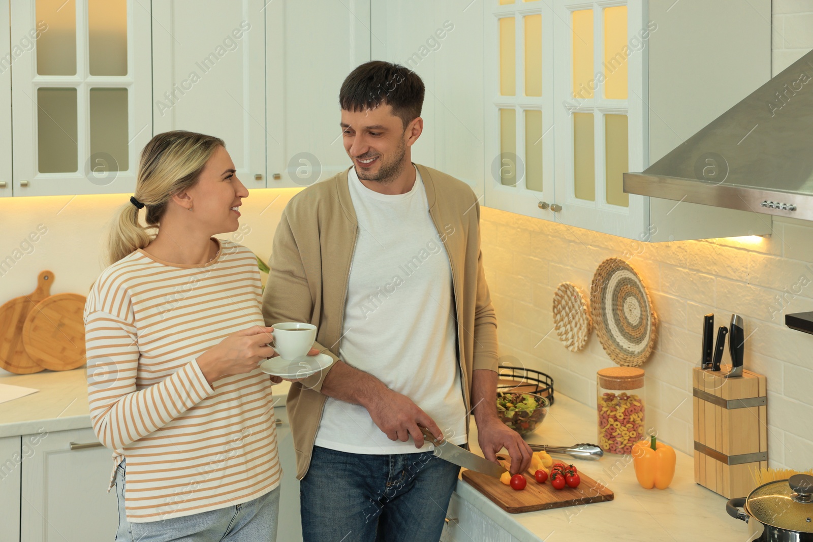 Photo of Happy couple spending time together while preparing food in kitchen